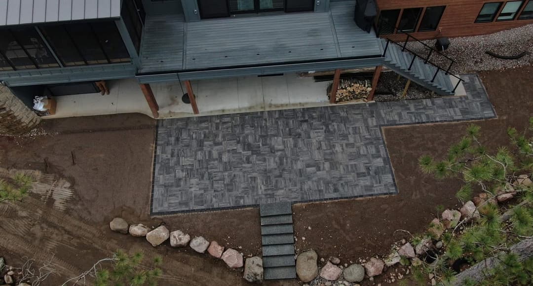 Aerial view of a modern home with a stylish stone patio and landscaped pathway.